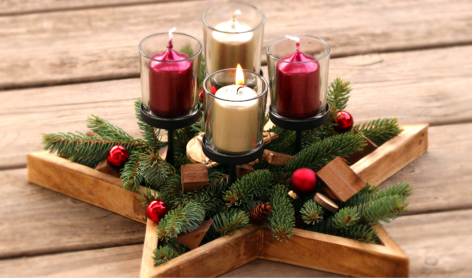 Advent candles sitting in a star with holiday greenery